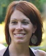 Audra Carabetta smiling with medium length reddish brown hair wearing a black halter top