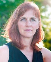 Dr. Jody Weber with medium length red/brown hair and blue eyes wearing a sleeveless black v-neck top